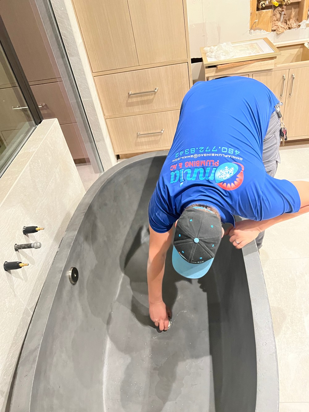 Omnia Plumbing technician installing the drain on a freestanding soaking tub during a master bathroom remodel.