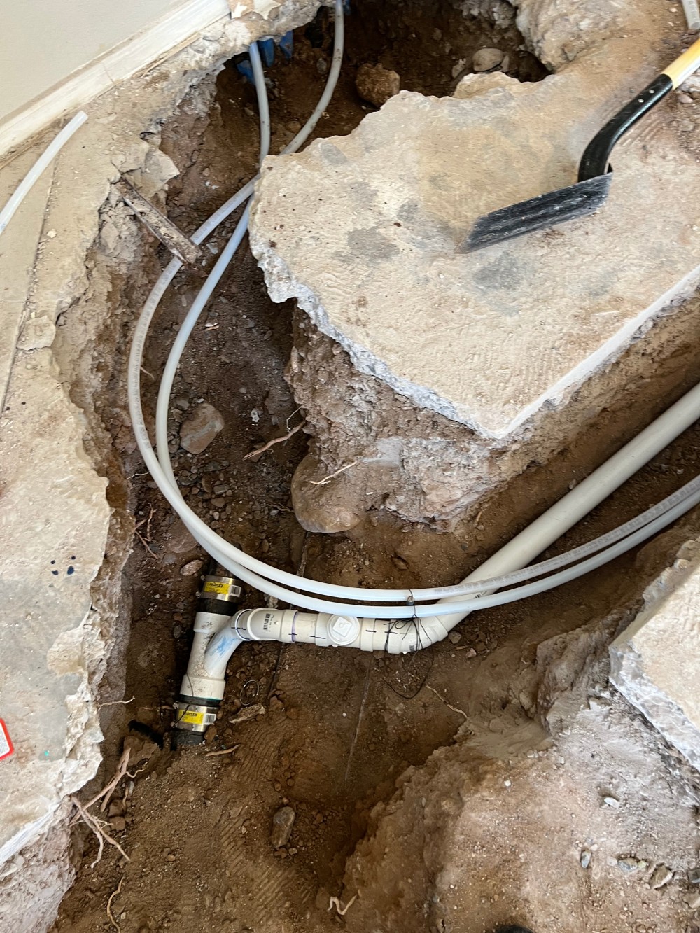 Slab leak repair in progress: concrete cut open exposing the copper supply line beneath the foundation.