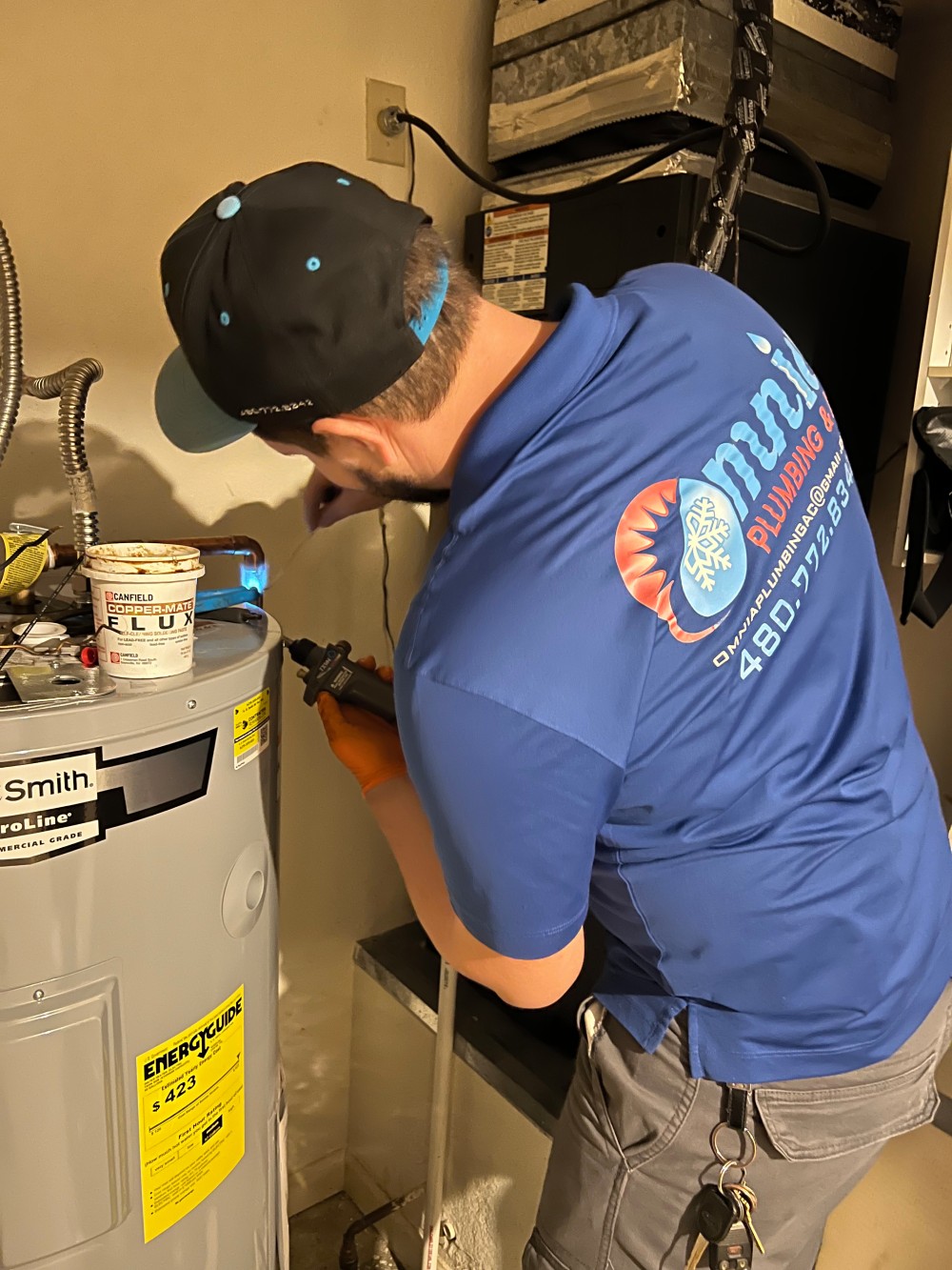Omnia Plumbing technician servicing a residential AO Smith electric water heater.